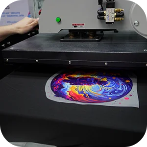 Heat press machine pressing a colorful DTF transfer onto a black t-shirt.