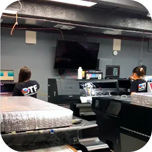 Two people operating DTF printers in an office, showcasing the production process.